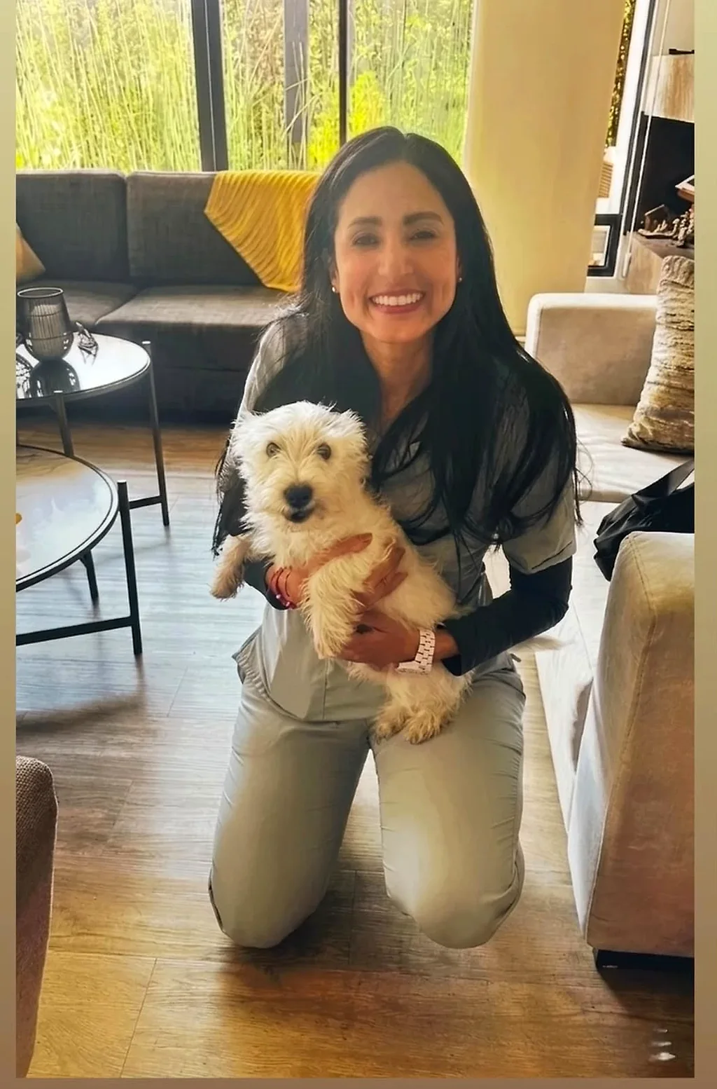 La Dra. Yoneidys Barrada sonriendo con un perro blanco en brazos, en casa